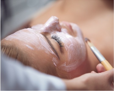 A woman receiving a facial mask treatment to rejuvenate her skin and enhance its appearance.