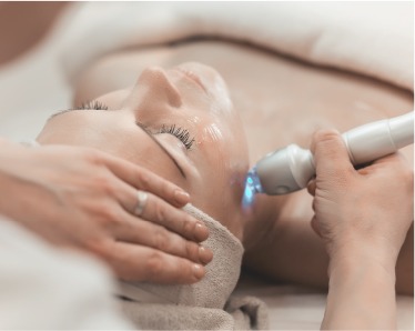 A woman receiving a facial treatment using an electric device to enhance her skincare routine.