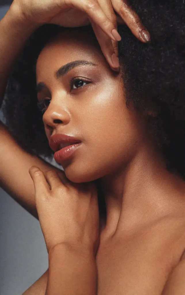A woman with an afro hair and a bare chest, exuding confidence and natural beauty
