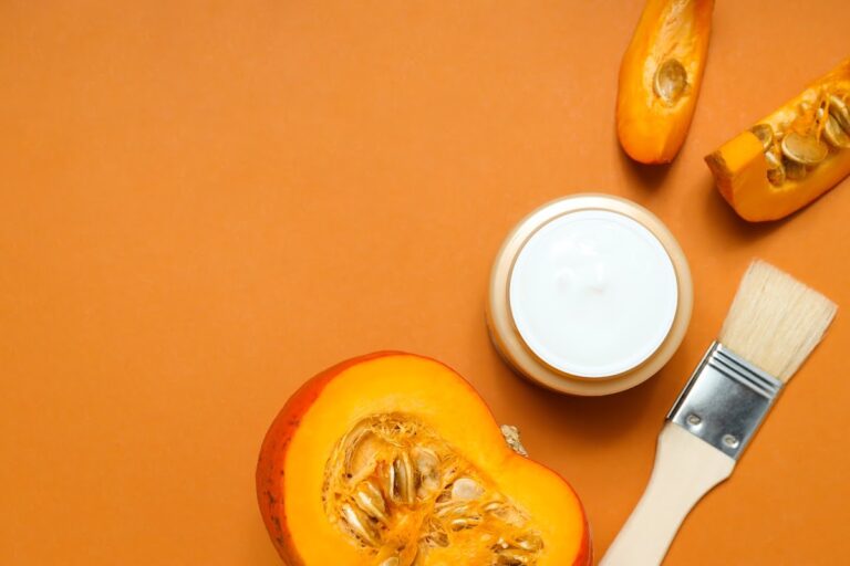 Skincare product with pumpkin and brush on an orange background.