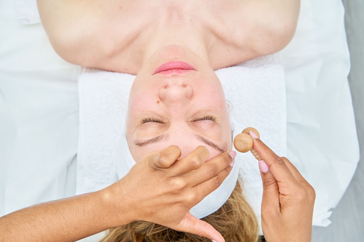 Woman receiving a calming face massage at a beauty salon.