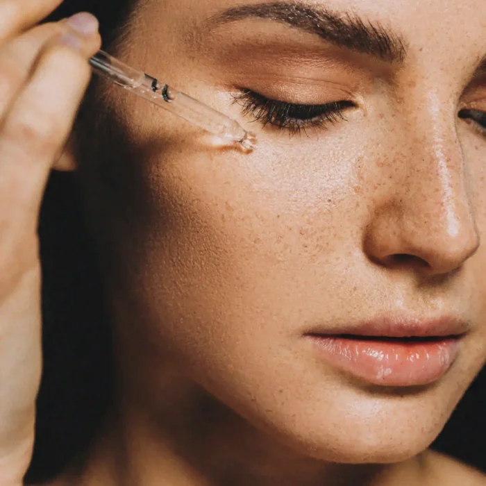 A woman applying makeup with a syringe, showcasing a unique beauty technique.